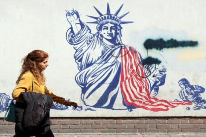 Una mujer camina junto a un mural antiestadounidense cerca de la antigua Embajada de EE. UU. en Teherán.