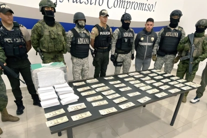 Agentes de Policía y Aduana exhiben el dinero y paquetes incautados durante el operativo en Quito.