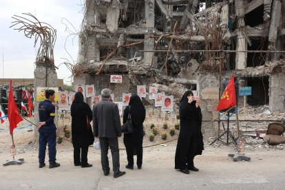 Varias personas se reúnen para observar fotografías de los fallecidos en un ataque aéreo estadounidense-israelí contra un edificio residencial, expuestas frente al mismo edificio que fue alcanzado en Teherán, Irán, el 13 de abril de 2026.