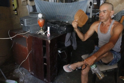 En el sur de Guayaquil, moradores del suburbio intentaron aliviar el calor con cualquier objeto ante la falta de energía eléctrica, que les impedía encender ventiladores.