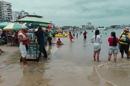 Turistas y locales disfrutan de un día de playa durante un feriado en la costa de Ecuador.