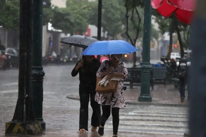 Personas se movilizan bajo la lluvia que sorprendió a la ciudad en horas de la tarde.