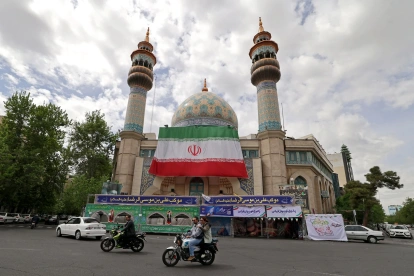 Varios automovilistas pasaron junto a la mezquita del Imam Sadiq (AS), cuya fachada lucía una enorme bandera iraní, en la plaza Palestina de Teherán.