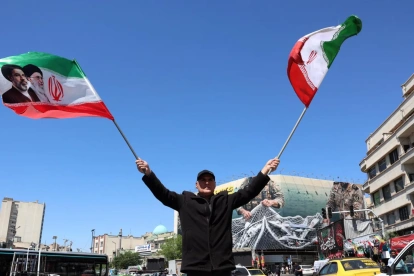 Un hombre ondea este miércoles 22 de abril de 2026, banderas iraníes en Teherán.