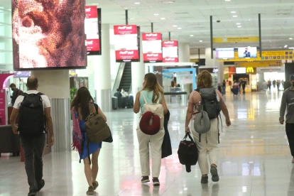 Personal aeroportuario y viajeros se movilizan hacia la terminal aérea con documentación de vuelo en medio de las restricciones nocturnas.