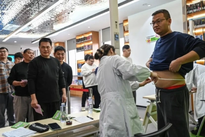 Participantes masculinos haciendo fila para pesarse y medirse la cintura en un centro comunitario local en Wuxi, en la provincia de Jiangsu, al este de China.