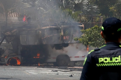 Un integrante de la Policía de Colombia observa un vehículo afectado por una explosión este 24 de abril de 2026, en Cali (Colombia).