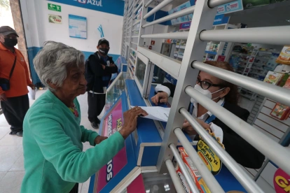 Una mujer de la tercera edad muestra una receta médica para comprar fármacos.