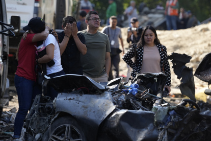 Familiares de las víctimas del atentado ocurrido en la Vía Panamericana lloran este domingo frente a los escombros de los vehículos destruidos en Cajibío (Colombia).