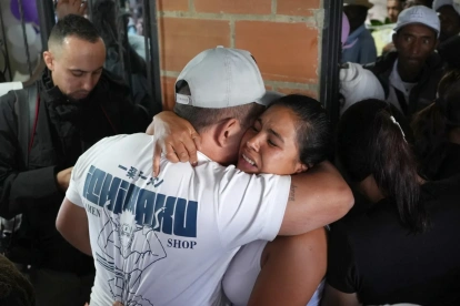 Personas se abrazan durante un velorio por las víctimas mortales de la explosión de un cilindro bomba en Cajibío (Colombia).