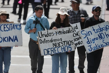 Personas sostienen carteles durante la masiva marcha por el Día Internacional del Trabajo, este viernes 1 de mayo de 2026, en Quito.