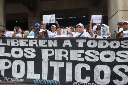 Personas sostienen carteles como parte de una manifestación para denunciar la situación de los presos políticos en cárceles de Venezuela este lunes, en Caracas (Venezuela).