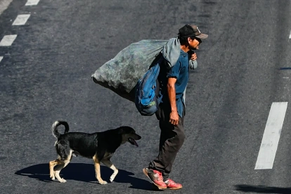 Un hombre camina junto a un perro por una calle del bulevar Fuerzas Armadas este jueves, en Tegucigalpa (Honduras).