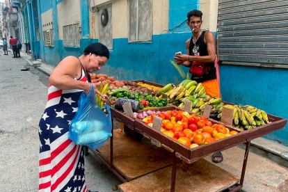 Una mujer vestida con los colores de la bandera de Estados Unidos compra frutas a un vendedor ambulante este viernes, en una calle de La Habana (Cuba).