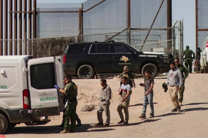 Migrantes detenidos son llevados por miembros de la Patrulla Fronteriza estadounidense a un vehículo, junto al muro fronterizo en El Paso, Texas (EE.UU).