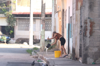 Una mujer limpió la vereda en el sector donde fue abandonado el cadáver de un hombre, frente a una escuela, en el Guasmo Sur de Guayaquil.