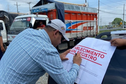 Una autoridad firma un sello que pusieron a una piladora que fue clausurada.
