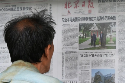 Un hombre lee un periódico en Pekín sobre la visita de Donald Trump a Xi Jinping.