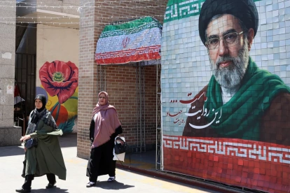Ciudadanas iraníes pasan junto a una fotografía del líder supremo iraní, el ayatolá Mojtaba Khamenei, en una calle de Teherán, Irán, el 18 de mayo de 2026.