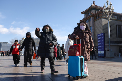 Personas caminan en las calles de Beijing, en China, al fondo un edificio.