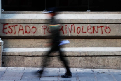 Un policía camina frente a un grafiti en La Paz, en medio de las protestas que marcan la primera crisis política del Gobierno de Rodrigo Paz.