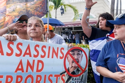 Cubanos en el exilio sostienen un cartel que dice "Asesinos y terroristas" mientras celebran el Día de la República de Cuba en Miami, Florida, EE. UU., el 20 de mayo de 2026.