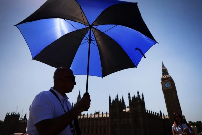Un hombre se protege del sol con un paraguas en Londres.