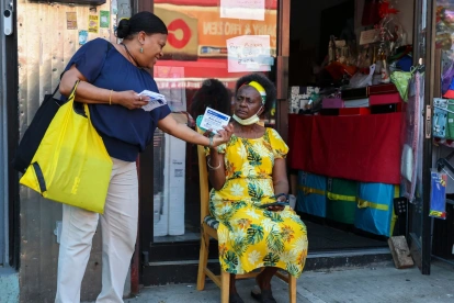 Una promotor (izquierda) entrega kits de herramientas comerciales para la Copa Mundial 2026 a una propietaria de un pequeño negocio en el barrio de Little Haiti, en Nueva York.