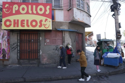 Unas personas pasan al pie de un negocio cerrado por el paro que hay en Bolivia.