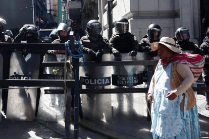 Una mujer aimara camina frente a un grupo de policías durante una protesta por quinta semana consecutiva este 1 de junio de 2026, en La Paz (Bolivia).