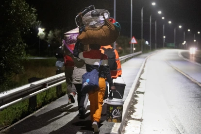 Inmigrantes cargando sus pertenencias caminan por una calle de Stanford, a unos 120 kilómetros de Ciudad del Cabo.