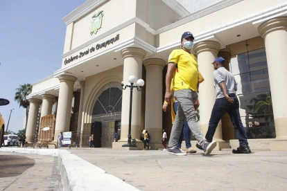 Personas caminan al pie del edificio del Gobierno Zonal de Guayaquil.