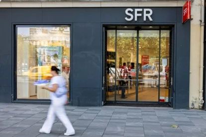 Una persona pasa al pide de una tienda de SFR.