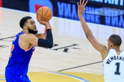 El pívot de los New York Knicks Karl-Anthony Towns tira al aro con la marca del alero de los San Antonio Spurs Victor Wembanyama