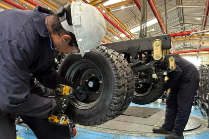 Un par de trabajadores cumplen su jornada en una fábrica de carros.