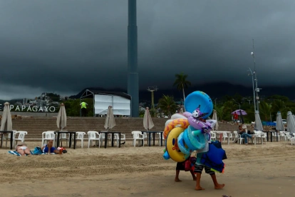 Fotografía referencial, vendedores caminan en una playa.