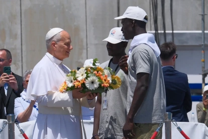 El papa León XIV recibe flores de dos voluntarios para protagonizar una ofrenda floral en el mar en recuerdo de los migrantes muertos.