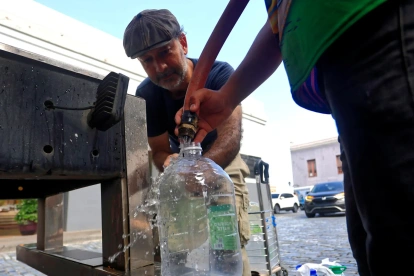 Personas se abastecen de agua tras la interrupción del servicio este lunes, en San Juan (Puerto Rico).