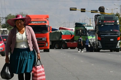 Una mujer quechua camina frente a vehículos de una caravana de transportistas para exigir el levante de los bloqueos de carreteras este lunes, en Cochabamba (Bolivia).
