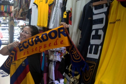 Una clienta sostiene una bufanda tricolor con el lema 