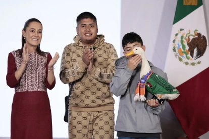 Carlos (d) sostiene al pato Merlín, vestido con una camiseta de la Selección Mexicana de Fútbol, junto a sus familiares Karla Gómez (i) y Cristian (2-d) durante una visita a la presidenta de México, Claudia Sheinbaum.