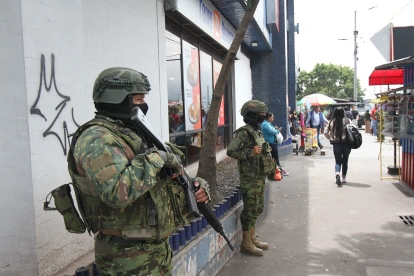 Dos militares resguardan una zona de afluencia de civiles en una ciudad.