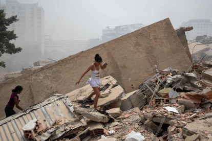 Personas caminan entre los escombros de edificios colapsados tras los terremotos en La Guaira, Venezuela.