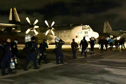 Fotografía cedida por la UNGRD que muestra a integrantes del grupo de búsqueda y rescate USAR COL-1 durante una operación logística nocturna en un avión militar.