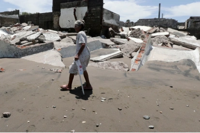 Una habitante de la aldea camina frente a escombros de casas destruidas en Cedeño, al sur de Honduras. El poblado lleva 30 años sufriendo el avance del mar.