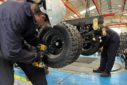 Un par de trabajadores cumplen su jornada laboral en una fábrica de carros.