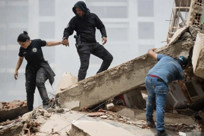 Personas caminan entre los escombros de edificios derrumbados en La Guaira tras los terremotos en Venezuela.