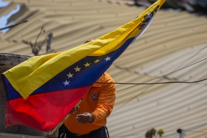 Un integrante de Protección Civil coloca la bandera de Venezuela en La Guaira tras los terremotos