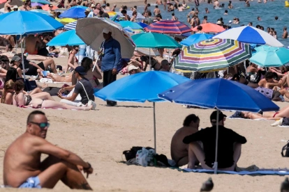 Turistas buscan sombra bajo sombrillas en playas europeas durante la ola de calor.
