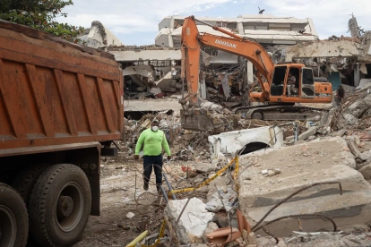 Una persona camina entre máquinas y escombros de edificios colapsados este lunes, en La Guaira (Venezuela).